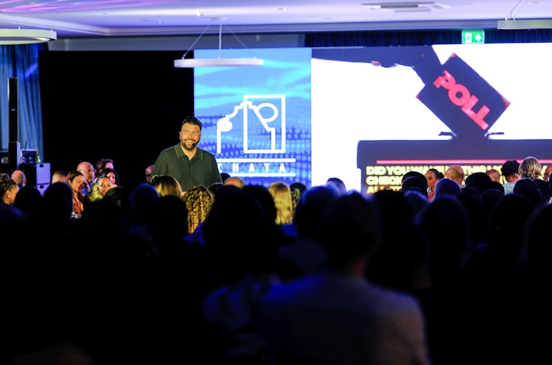 Speaker on stage addressing a large audience with confidence